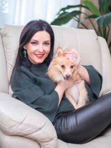 Portrait of mature beautiful woman sitting at home with her lovely pet pomeranian dog. Orange puppy with brunette lady.